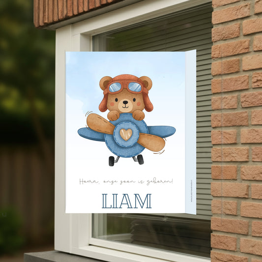 Geboortebord voor op het raam met naam en de afbeelding van een schattig beertje in een vliegtuig.