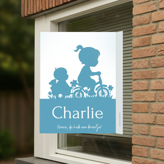 Geboortebord voor op het raam met een silhouet van een zusje met haar broertje op de fiets.