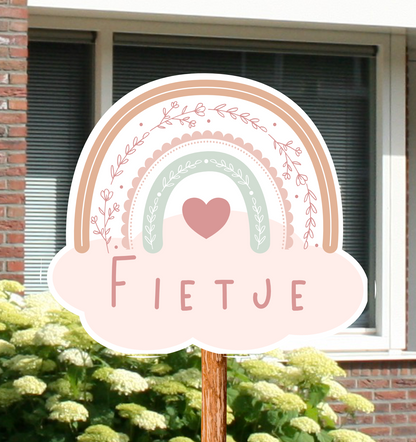 Geboortebord voor in de tuin met naam en de illustratie van een regenboog in roze kleuren.